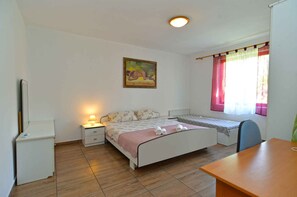 Cozy retreat with a single bed, bedside table, and a window with sheer curtains.