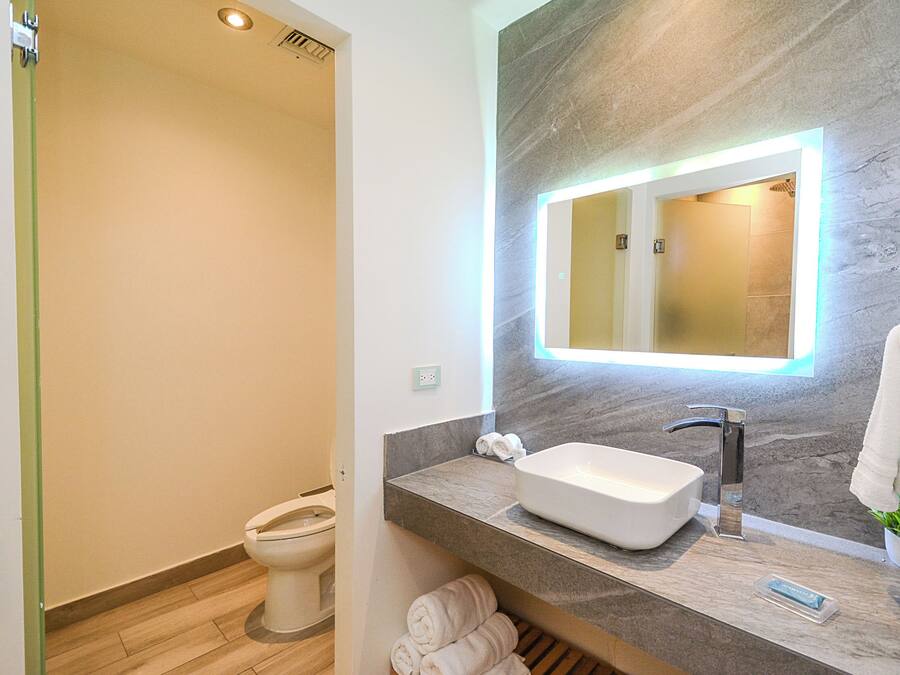 Un bagno moderno con lavabo integrato, uno specchio e zona doccia.