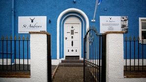 A blue building with a white door and a sign that reads "St. Andrews Guest House." - St Andrews Guest House (Irvine)