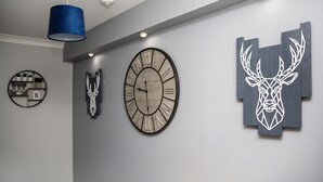 A modern interior with a large wall clock, decorative wall art, and a blue pendant light. - St Andrews Guest House (Irvine)