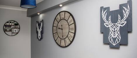 A modern interior with a large wall clock, decorative wall art, and a blue pendant light.