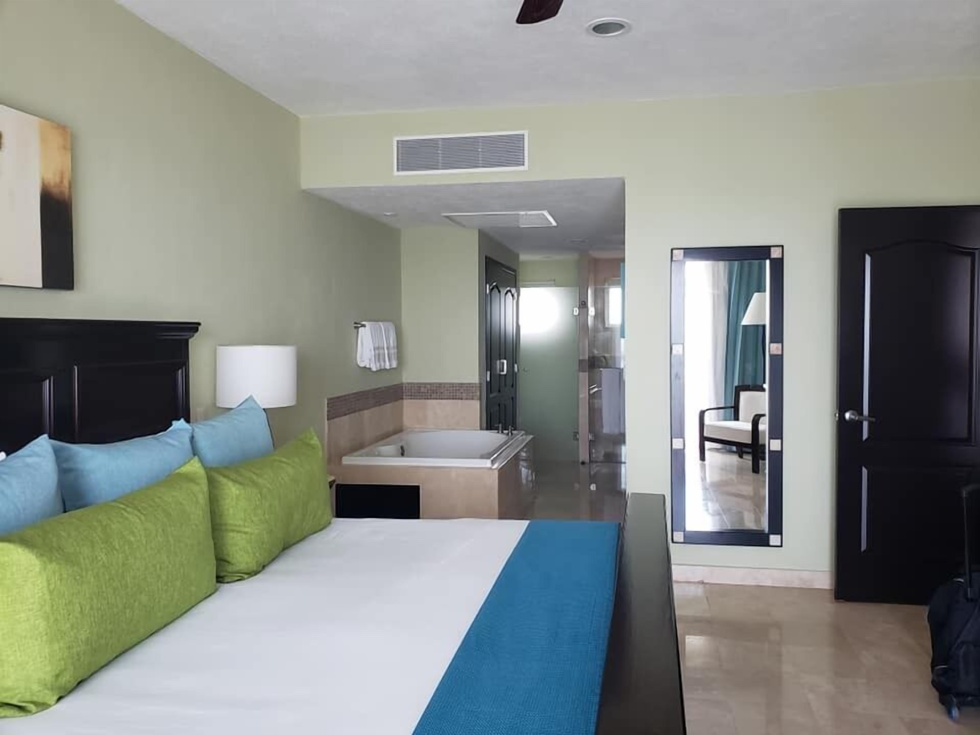 Una habitación de hotel con cama, baño y vista al pasillo.