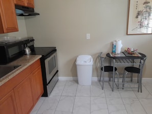 Compact kitchen with microwave, oven, and stove, adjacent to a dining area with a table and two chairs.