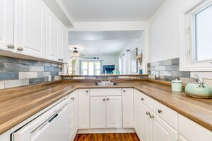 A modern kitchen with white cabinets, a wooden countertop, and a Bosch dishwasher.