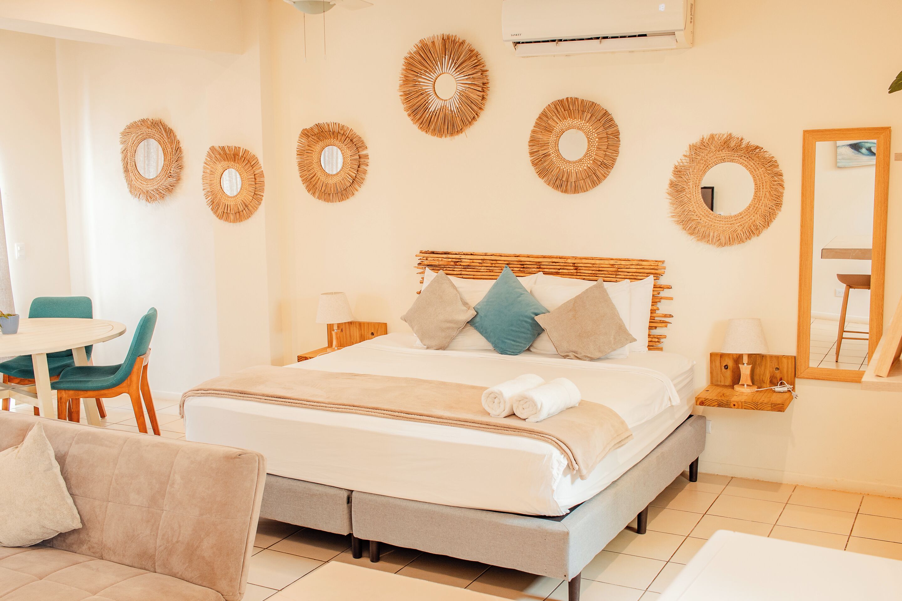 A neatly arranged bedroom with a bed, bedside tables, and a dining area.