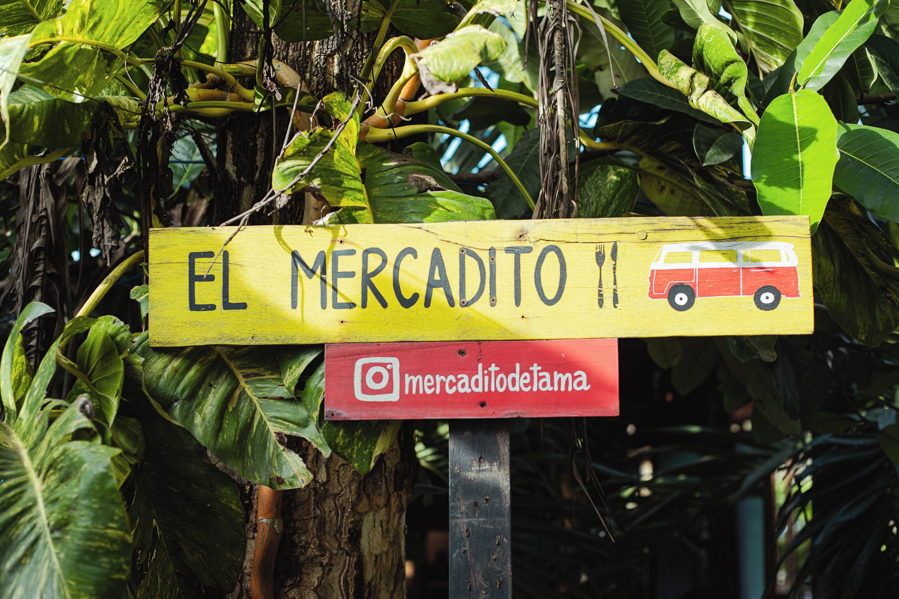 Un letrero de madera con el texto "EL MERCADITO 11" y un nombre de usuario de Instagram.