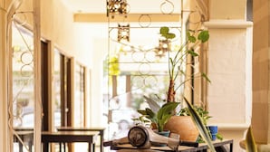 A hallway with a vintage scooter cart, potted plants, and a decorative metal gate. - Zulu Surf Hotel (Tamarindo)