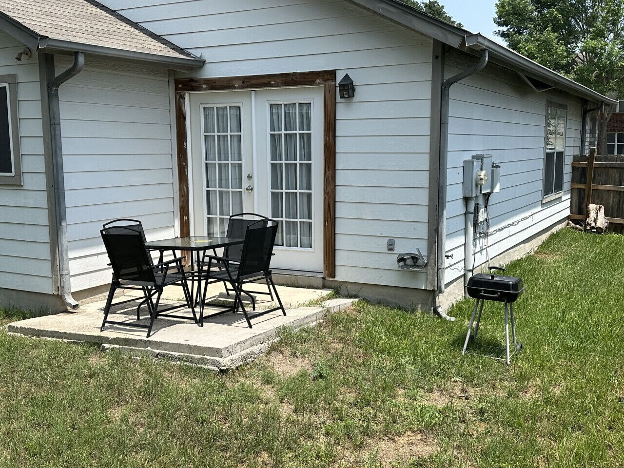 Una casa con patio, parrilla y zona de estar cubierta al aire libre.
