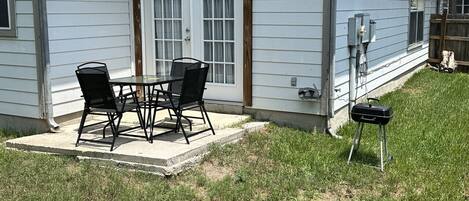 Una casa con patio, parrilla y zona de estar cubierta al aire libre.