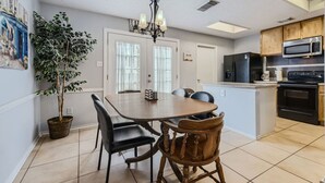 Una cocina moderna con comedor, que incluye una lámpara de araña, una isla grande y electrodomésticos integrados.