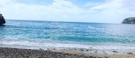 A rocky beach with calm sea and clear skies.