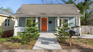 A single-story house with a red door, a front porch, and a mailbox.