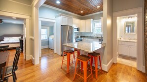 A modern kitchen with a central island, wooden flooring, and white cabinetry.