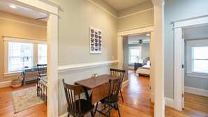 A dining area with a wooden table and chairs, a rug, and a wall-mounted picture.