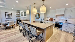 A modern kitchen with a central island, bar stools, pendant lighting, and a stainless steel oven. - Gulfside Place #107 ~ 3br/3ba - Gulf front living at its finest (Sanibel)