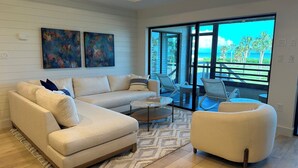 A living room with a sofa, a round coffee table, and a chair. There are two abstract paintings on the wall. - Gulfside Place #107 ~ 3br/3ba - Gulf front living at its finest (Sanibel)