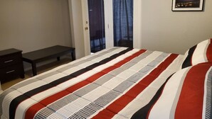 Une chambre à coucher avec un lit, un banc, une armoire et une porte avec des rideaux.