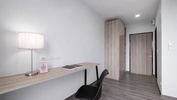 A modern, minimalist room with a wooden desk, a black chair, and a lamp.
