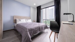 A modern hotel room with a bed, a desk, and a chair. - Aqua Residences (Bangkok)