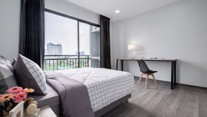 A modern hotel room with a large bed, a desk, and a chair. - Aqua Residences (Bangkok)