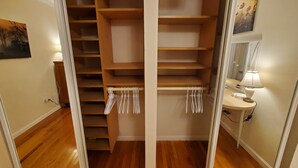 A walk-in closet with wooden shelves and a hanging rod for clothes. - No parties, quiet, 3 bed, 2 bath. (St. Louis)