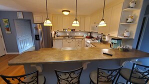 A kitchen with a central island, bar stools, hanging pendant lights, and a refrigerator. - No parties, quiet, 3 bed, 2 bath. (St. Louis)