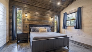 A bedroom with a wooden ceiling, a bed with gray bedding, two bedside tables, and a window with curtains. - Cabin Therapy - Luxury Cabin Near ATV Trails (Broken Bow)