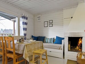 Een gezellige kamer met een eettafel, stoelen, een bank en een open haard.