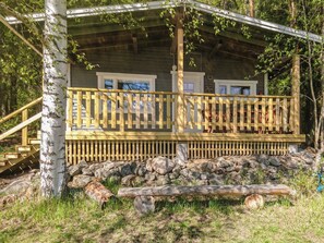 Una cabaña con terraza de madera, cimientos de piedra y entorno natural.