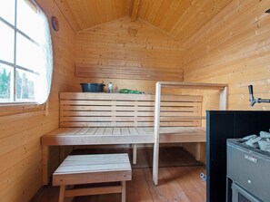 Een houten sauna met banken, een sauna-oven en een raam.
