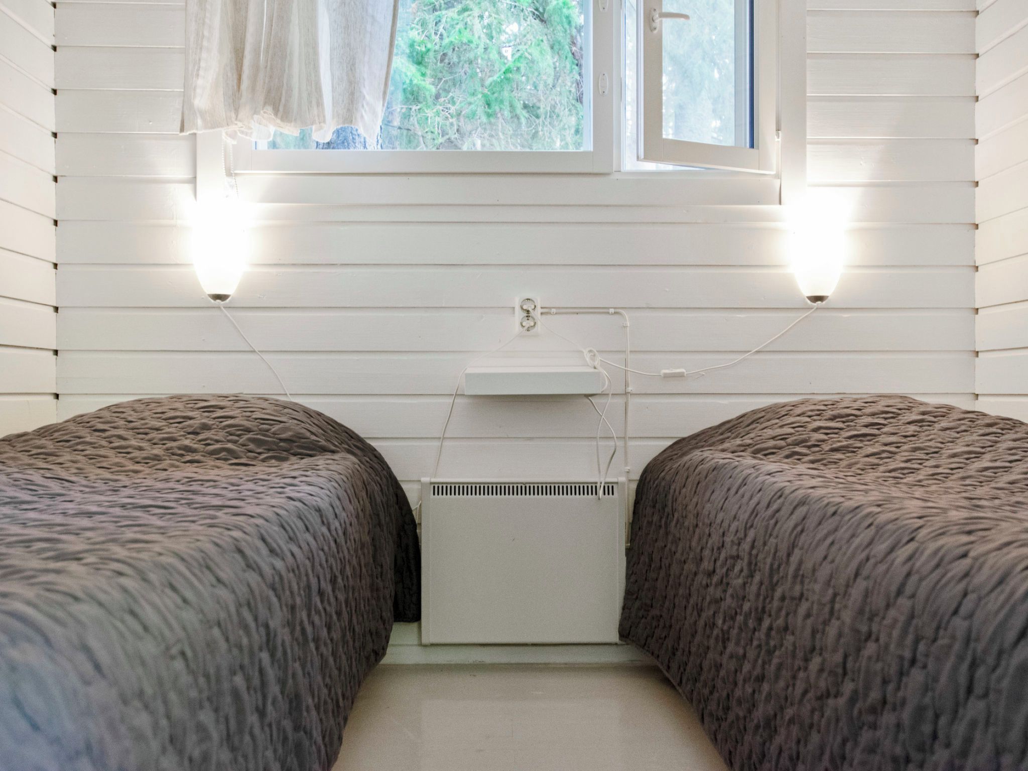 A bedroom with two beds, a window, and a radiator.