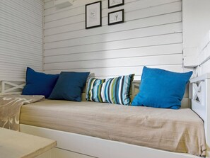 A white wooden bench with cushions, a small table, and framed artwork on the wall. - Vacation home Lepola by Interhome (Virrat)