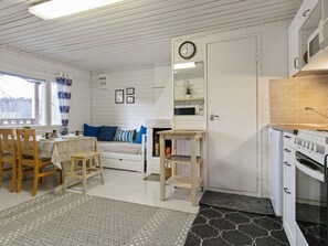 Un espacio habitable compacto con comedor, kitchenette y zona de estar con sofá y cojines.