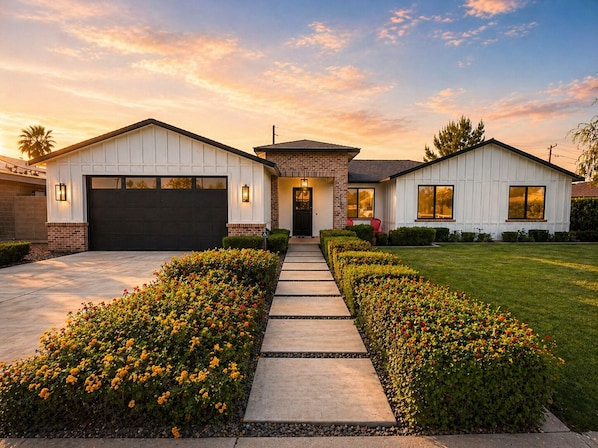 A two-story house with a garage, a front porch, and a well-maintained lawn.