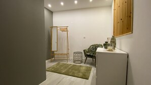 A modern bathroom with a wooden drying rack, a chair, a small round table, and a cabinet. - Remarkable 2-Bed House in Ponta Delgada (Ponta Delgada)