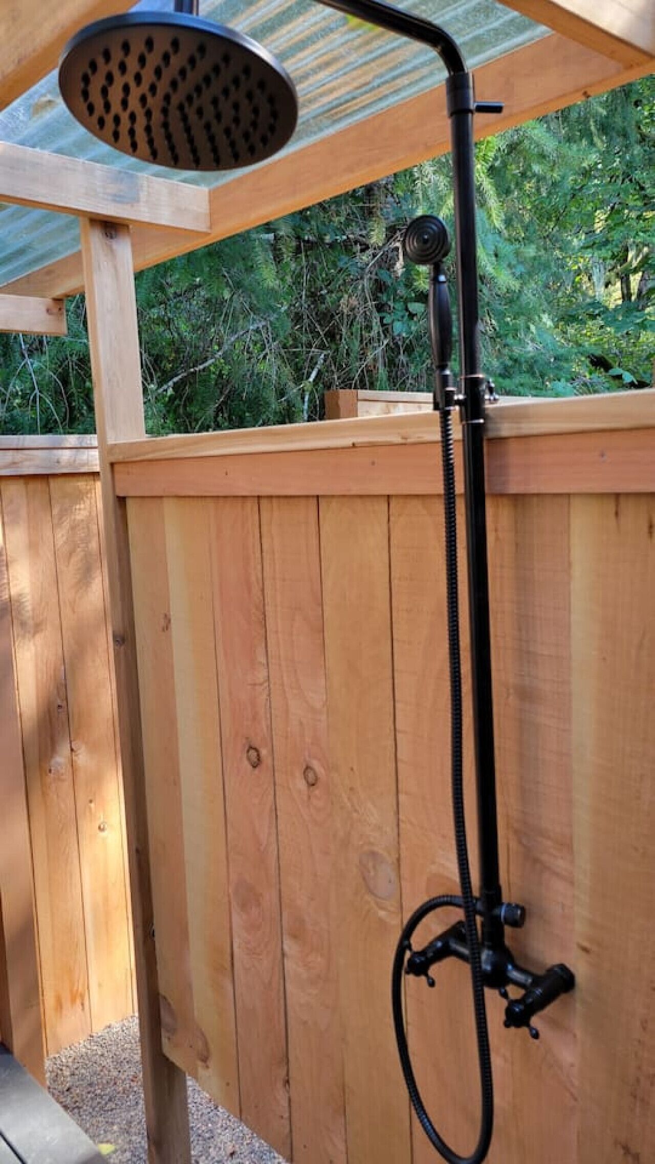 A wooden deck with a black hose showerhead and flexible hose.