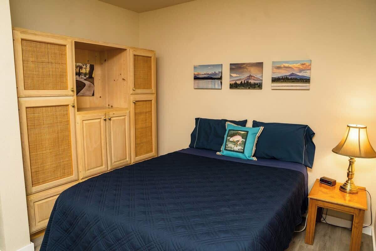 Ein Schlafzimmer mit einem Bett, einem Nachttisch mit Lampe und einem Kleiderschrank mit Spiegel.