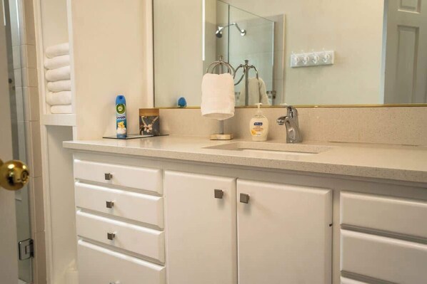 A bathroom with a sink, mirror, towel rack, and storage drawers.