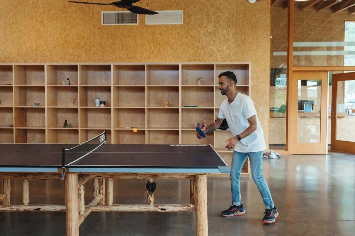 A ping pong table in a room with wooden shelves and a ceiling fan.