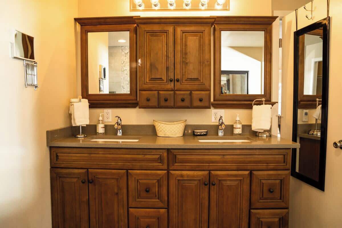 A bathroom with a double sink vanity, wooden cabinets, and two large mirrors.