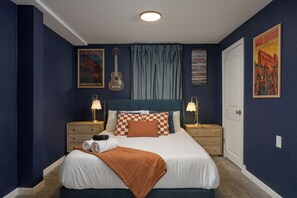 A bedroom with a bed, two nightstands, a guitar, a poster, and a door. - Stay Golden! ☀Family Retreat☀ New Hot Tub! + Sleeps 12 (Wheat Ridge)