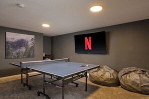 A ping pong table with a TV and a picture frame on the wall.