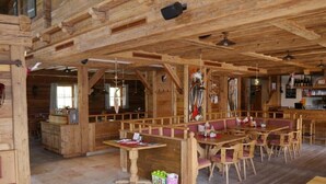 Ambiente interno in legno con zona bar, posti a sedere e camino.