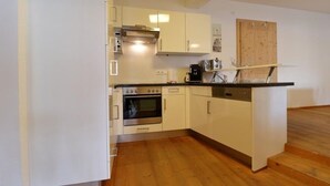 Una cucina compatta con pensili bianchi, forno integrato e lavastoviglie.