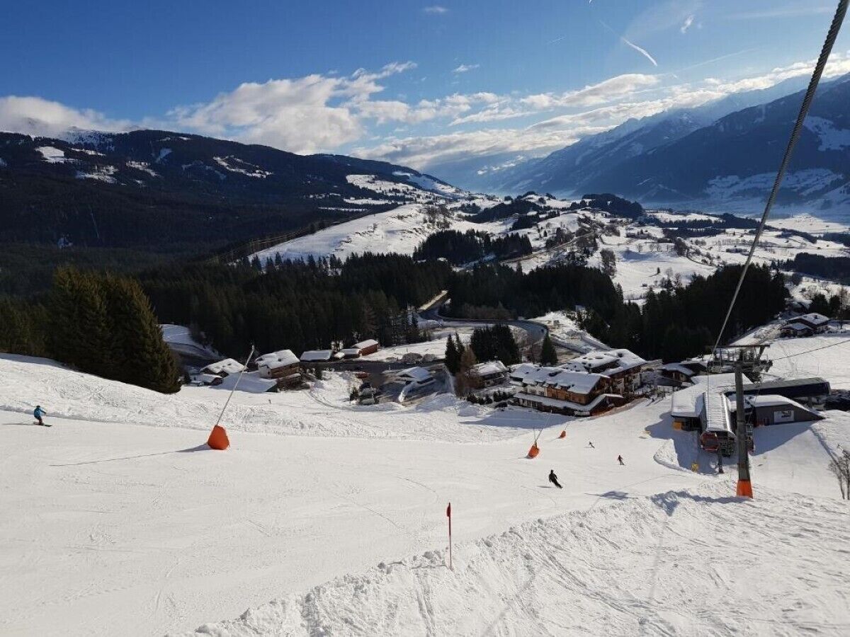 Ein Skigebiet mit Sessellift, schneebedeckten Pisten und Gebäuden im Hintergrund.