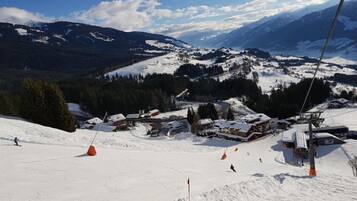 Ein Skigebiet mit Sessellift, schneebedeckten Pisten und Gebäuden im Hintergrund.