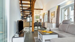 A modern living room with a staircase, a dining area, and a sofa. - Holiday flat "Landhaus Ameisberg" with mountain view, garden and Wifi (Mitternschlag)