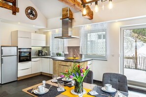 Una cocina moderna con armarios blancos, una isla central y una zona de comedor con una mesa preparada para dos.