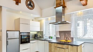 A modern kitchen with white cabinets, a stainless steel range, and a wooden island. - Holiday flat "Landhaus Ameisberg" with mountain view, garden and Wifi (Mitternschlag)