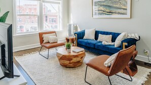 A living room with a blue sofa, two leather chairs, a wooden coffee table, and a painting on the wall. - Comfortable and Trendy Design 1BR in Lincoln Square (Chicago)